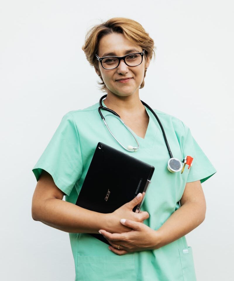 Confident female nurse with eyeglasses holding a tablet and stethoscope. Ideal for healthcare-related content.