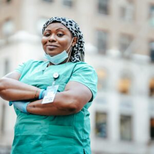 Proud nurse with arms crossed, in uniform, outdoors, urban setting, showing confidence and professionalism.